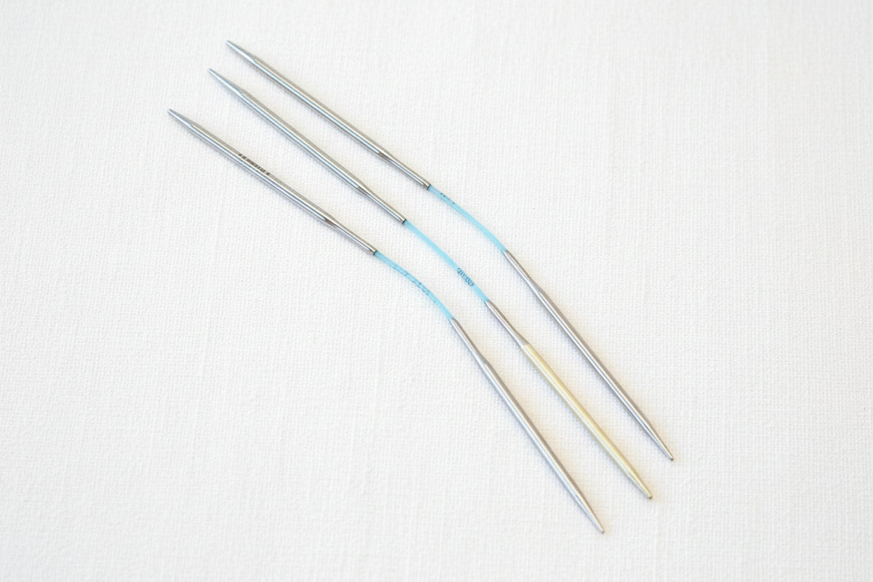 Set of metal knitting needles on a white background