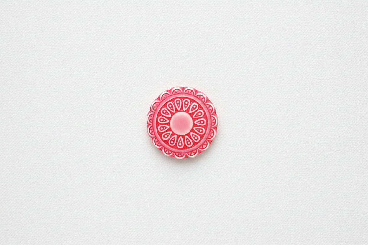 Red decorative circular flower design on a white background