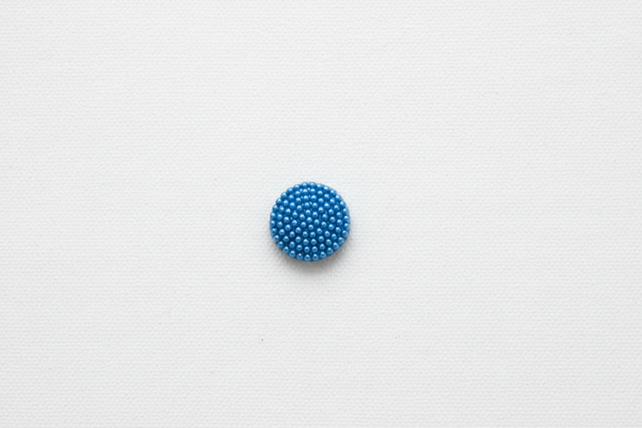 Blue beaded button on a white background