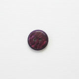 Round purple button with two holes on a white background
