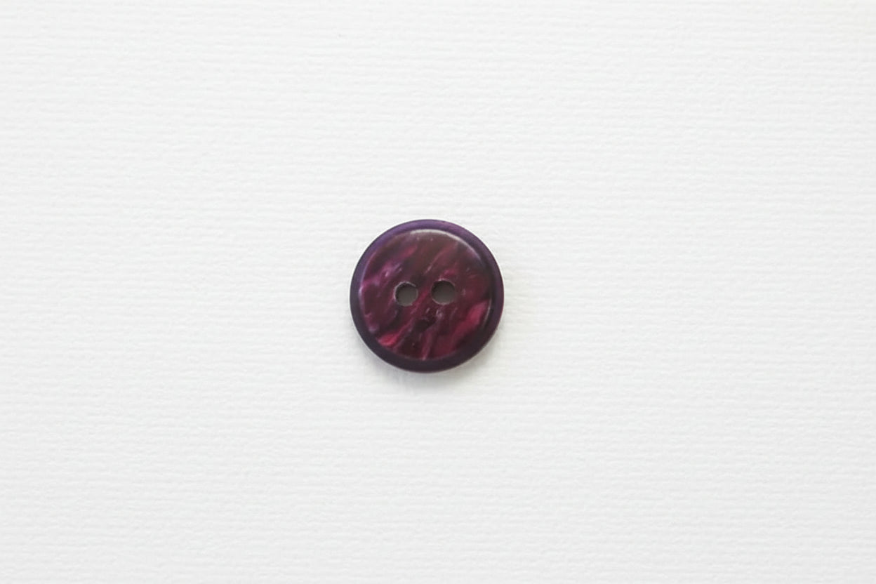 Round purple button with two holes on a white background