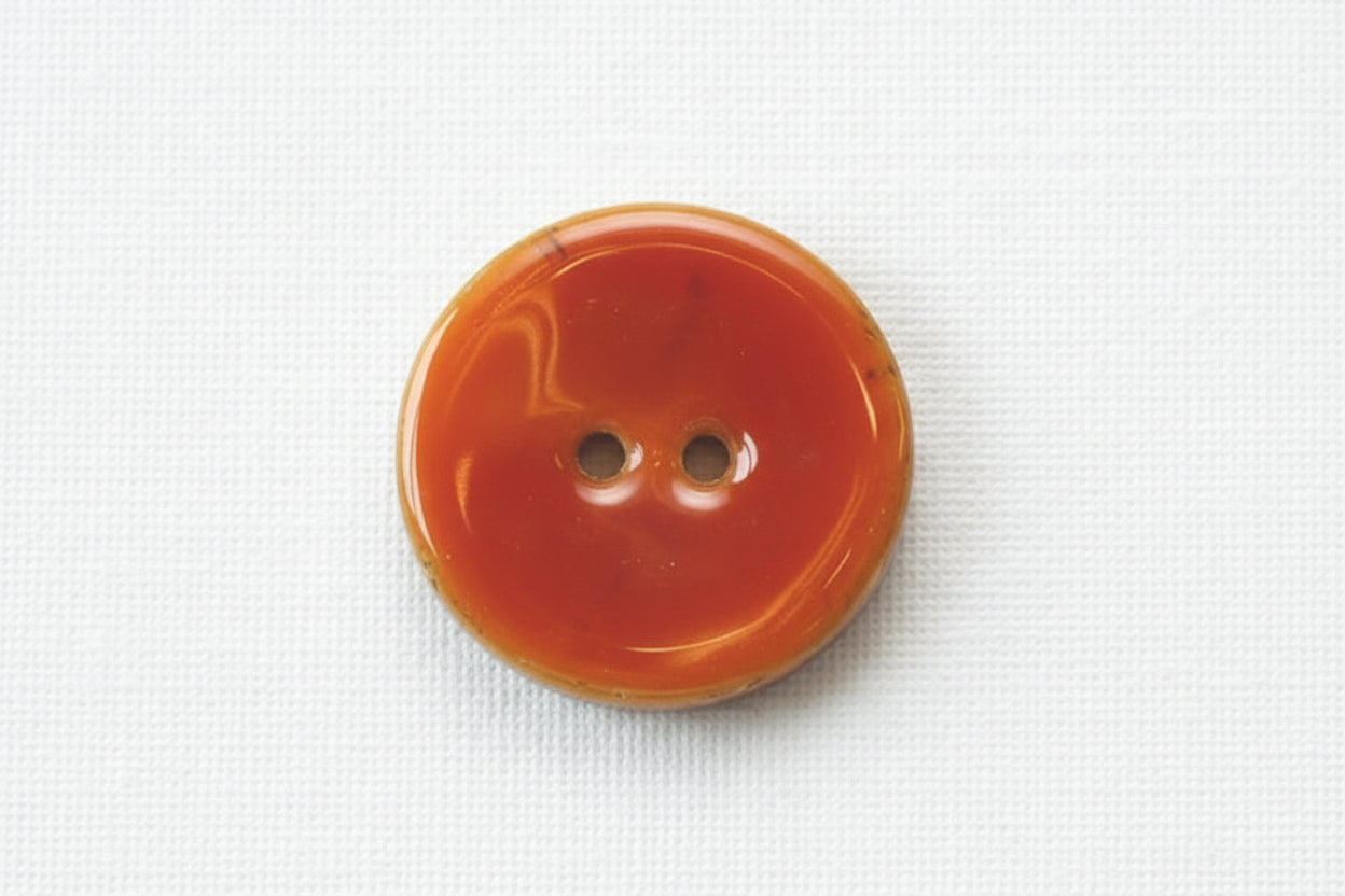 Orange button with two holes on a white background