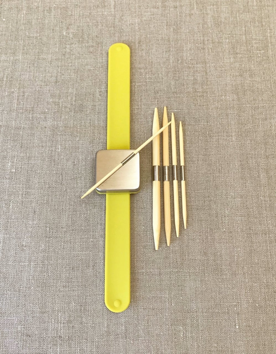 Yellow magnetic bracelet with cable needle attatched to the magnet