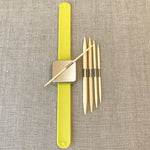 Yellow magnetic bracelet with cable needle attatched to the magnet