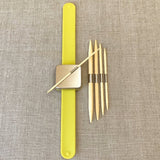 Yellow magnetic bracelet with cable needle attatched to the magnet