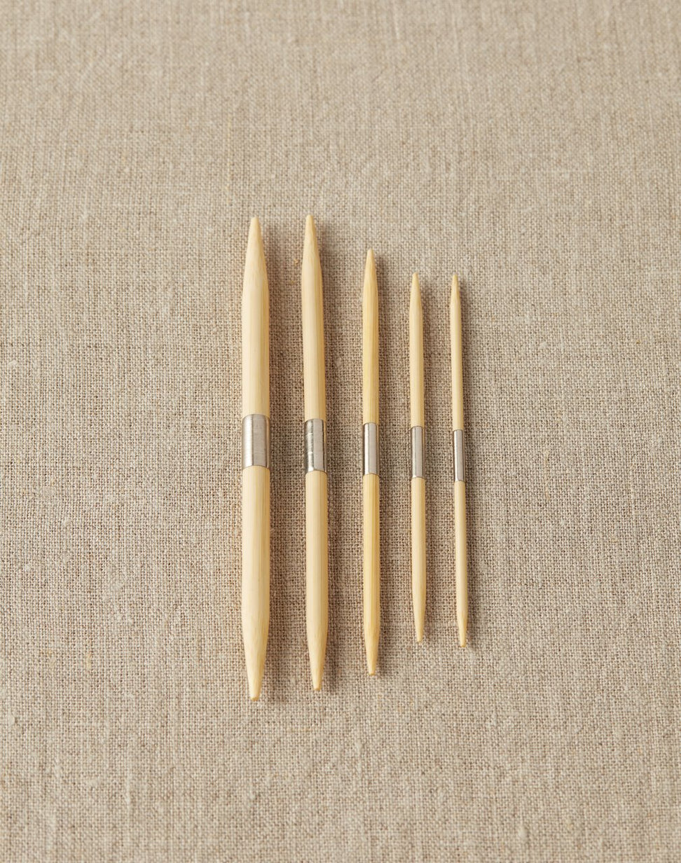 Set of wooden cable needles on a beige fabric background
