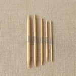 Set of wooden cable needles on a beige fabric background