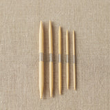 Set of wooden cable needles on a beige fabric background