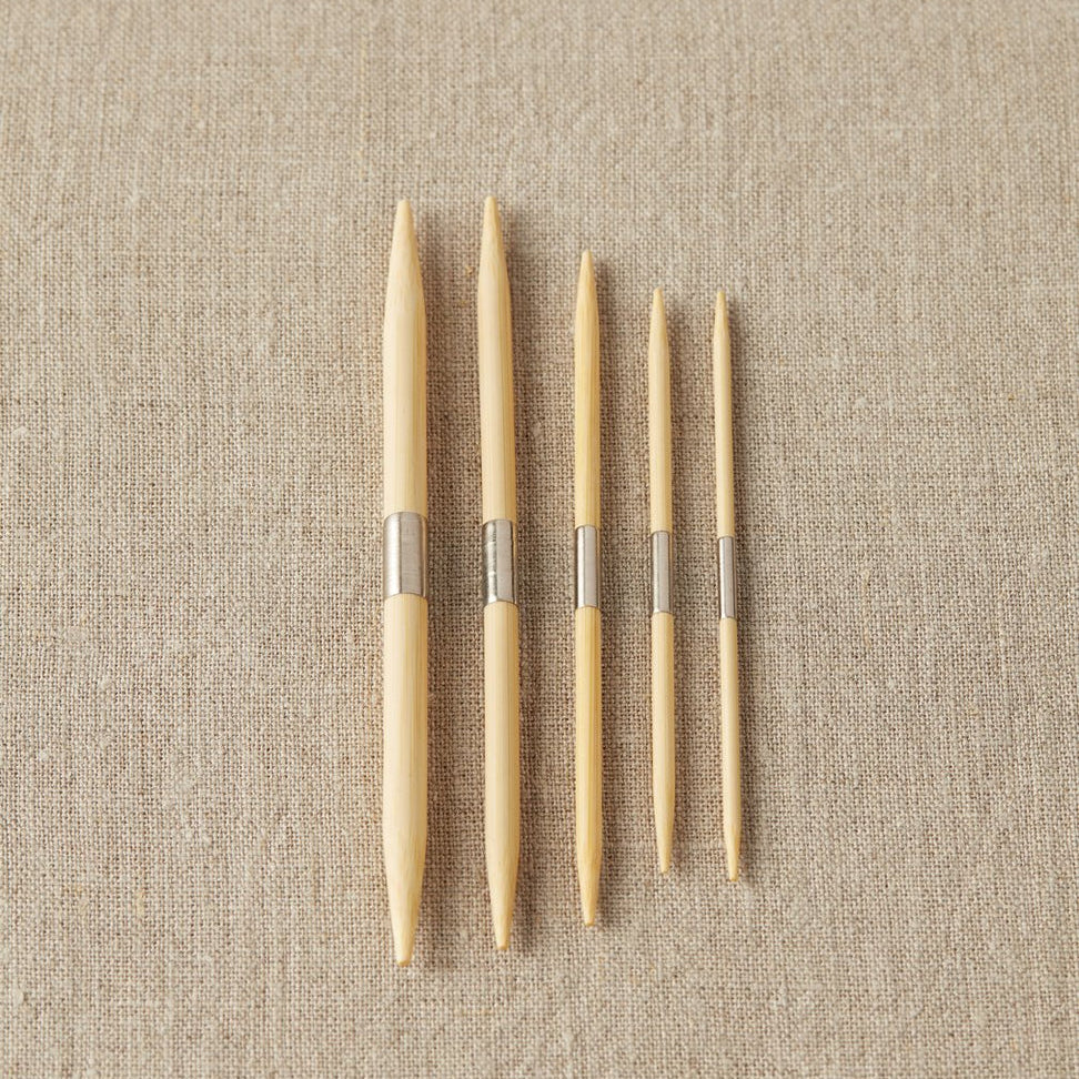 Set of wooden cable needles on a beige fabric background