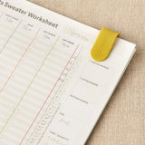 Sheet of paper with a sweater pattern  worksheet slipped together on a textured surface