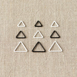 Set of triangle-shaped stitch markers on a beige fabric background