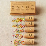 Set of stitch markers with packaging on a fabric background