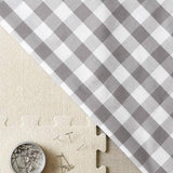 Gray and white checkered fabric with a coin and puzzle piece on a beige background