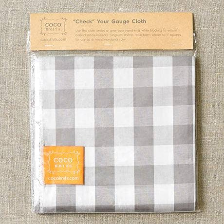 Packaged checkered cloth with COCO label on a textured fabric background