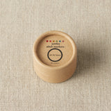 Round wooden container with 'jumbo stitch markers' label on a beige fabric background