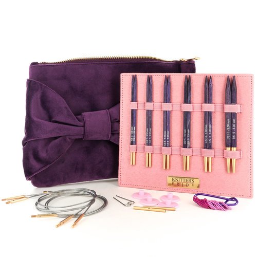 Purple clutch bag with a bow, pink case holding knitting needles, and additional needles on a white background