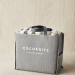 Gray tote bag with 'Cocoknits' branding on a beige background