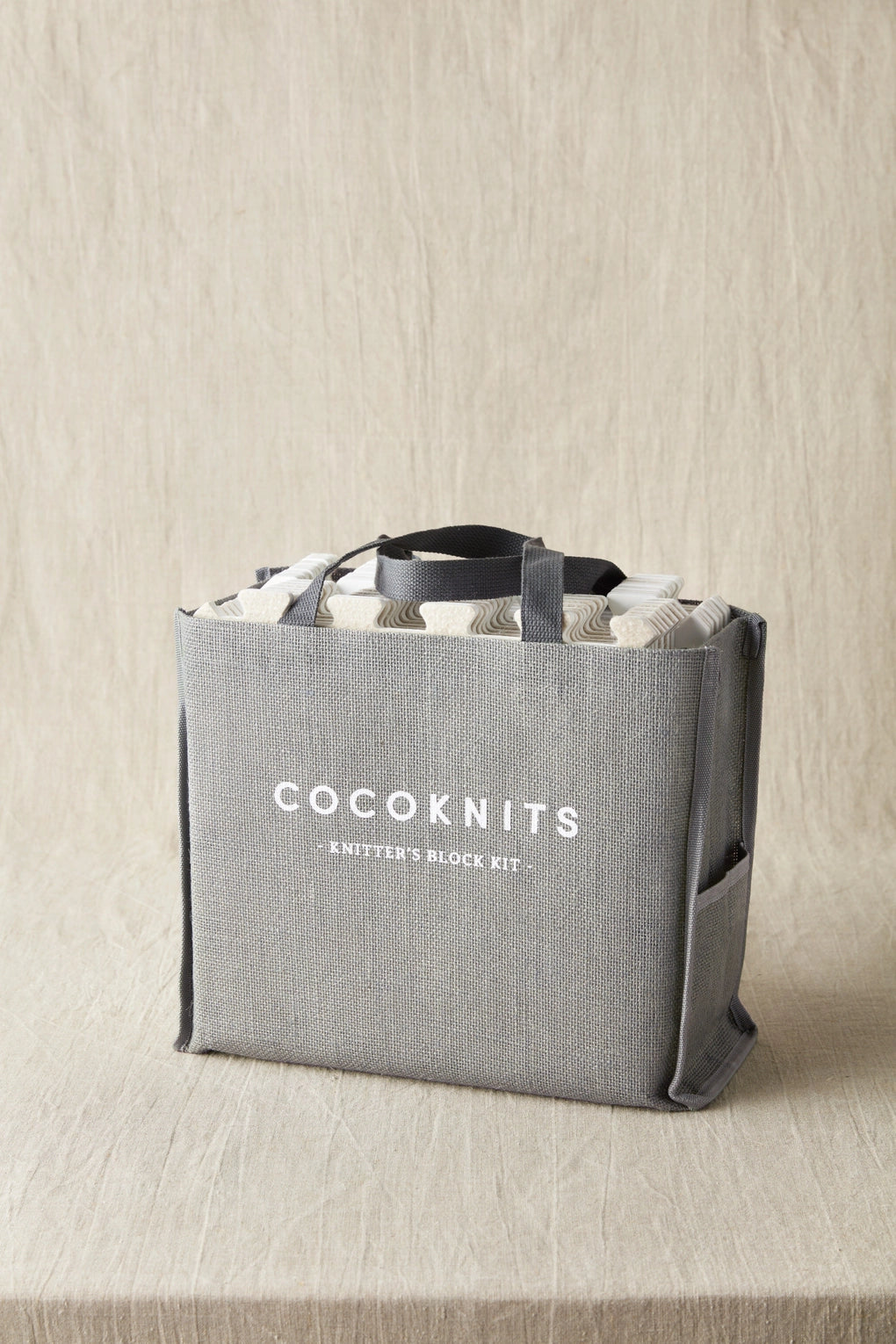 Gray tote bag with 'Cocoknits' branding on a beige background