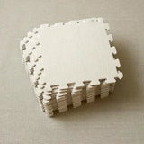 Stack of white foam blocking mats on a beige surface