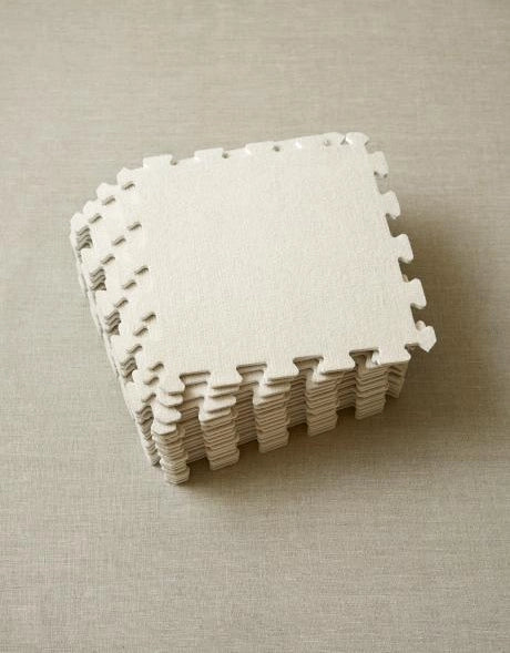 Stack of white foam blocking mats on a beige surface
