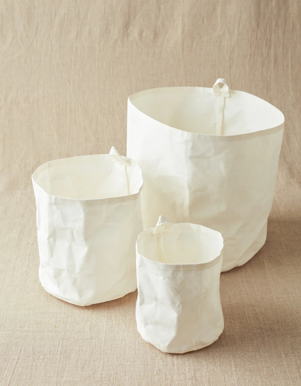 Three white textured kraft bins on a beige surface