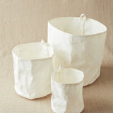 Three white textured kraft bins on a beige surface