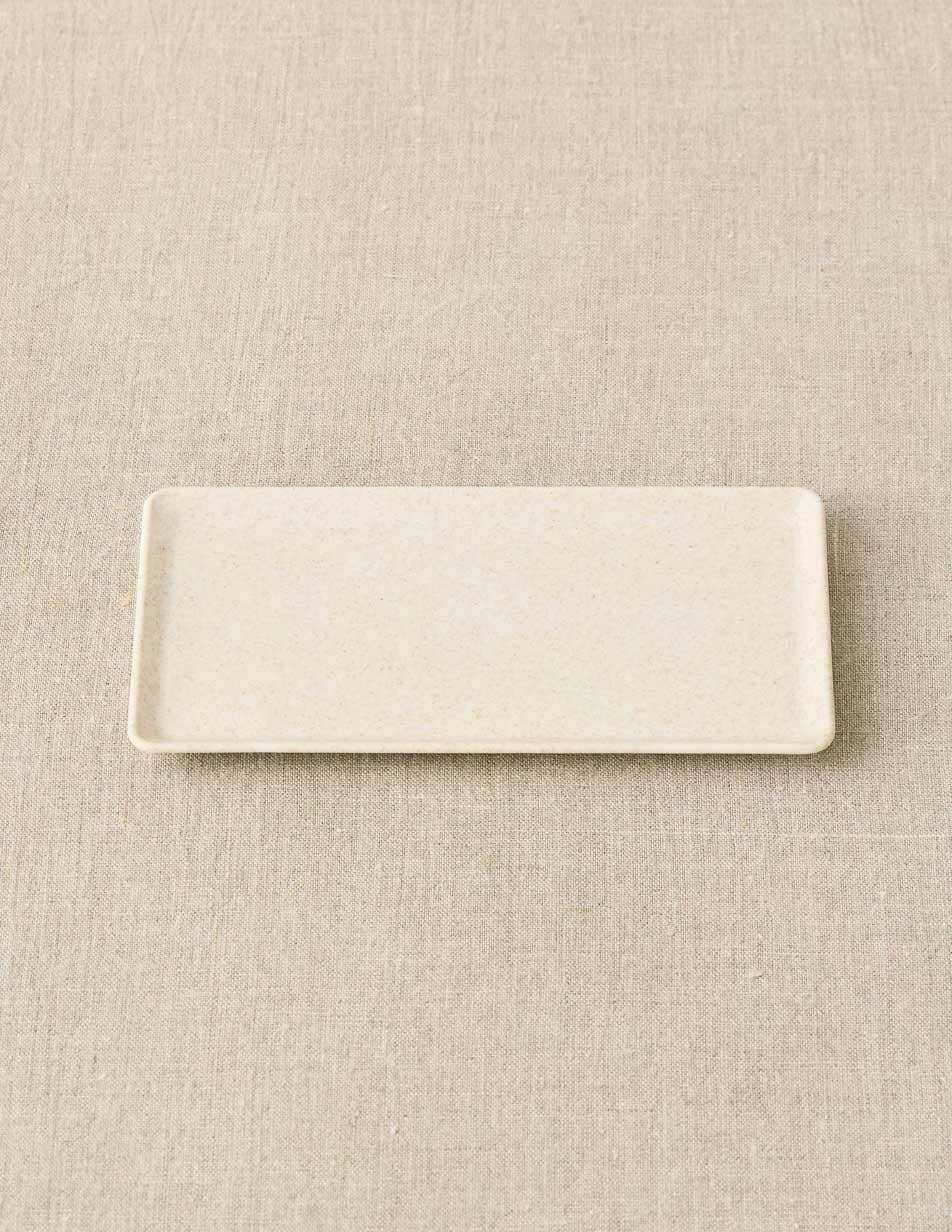 Rectangular ceramic plate on a beige textured surface