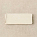 Rectangular ceramic plate on a beige textured surface