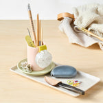 Notions tray with stationery items on a light wooden surface