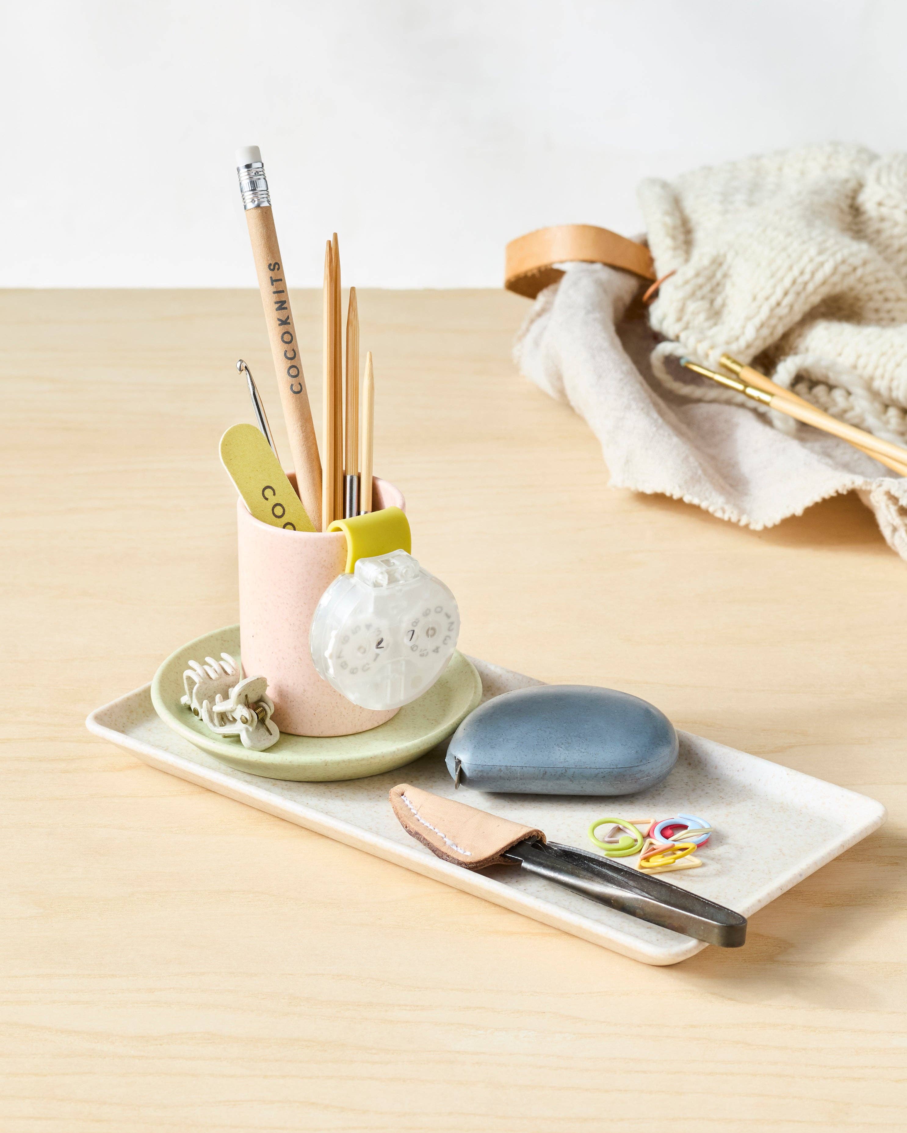 Notions tray with stationery items on a light wooden surface