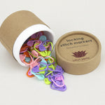 Colorful locking stitch markers in an open cardboard tube with 'lotus yarns' branding.