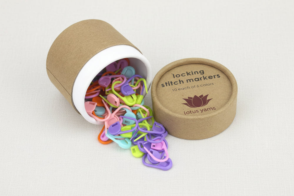 Colorful locking stitch markers in an open cardboard tube with 'lotus yarns' branding.