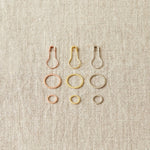 Set of metal ring and opening stitch markers on a beige fabric background