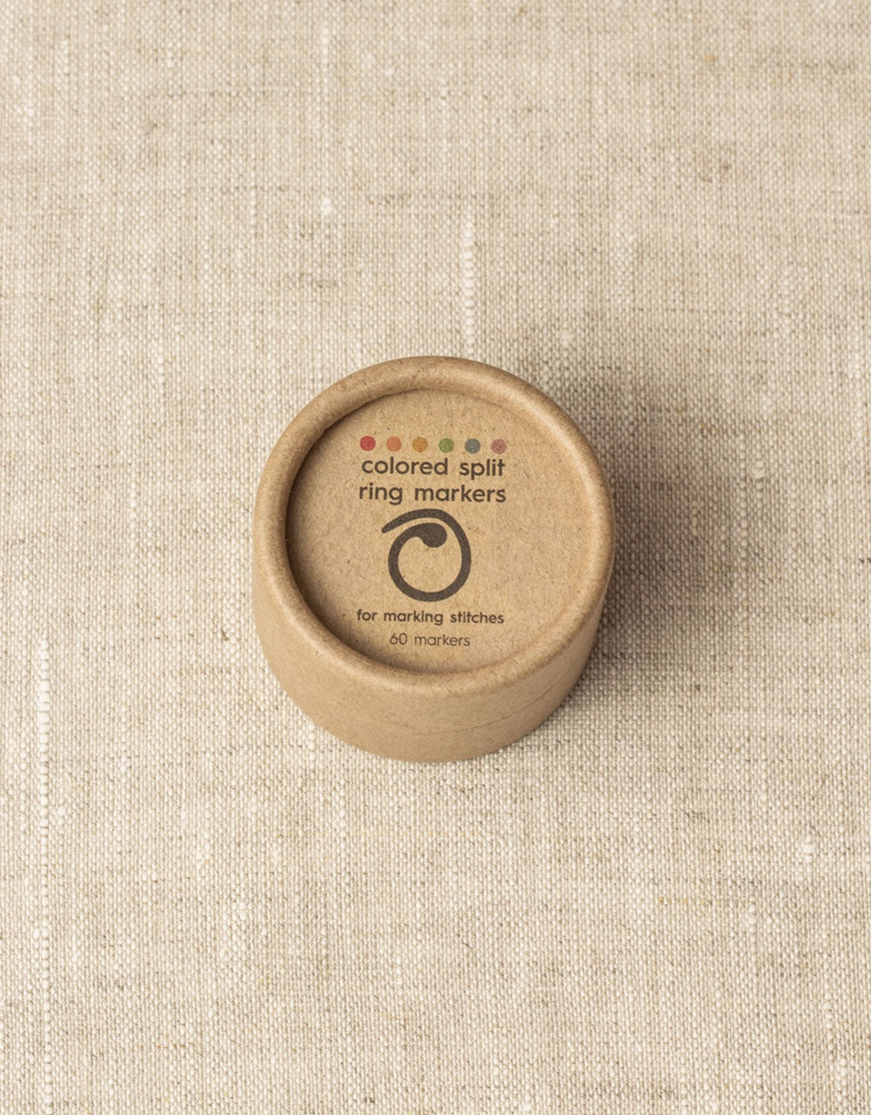 Brown container with 'colored split ring markers' text on a beige fabric background