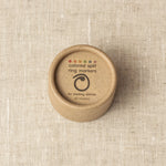 Brown container with 'colored split ring markers' text on a beige fabric background