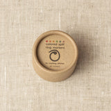 Brown container with 'colored split ring markers' text on a beige fabric background