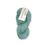 Teal skein of bulky weight yarn with a label on a white background