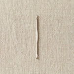 Silver crochet hook on a beige fabric background