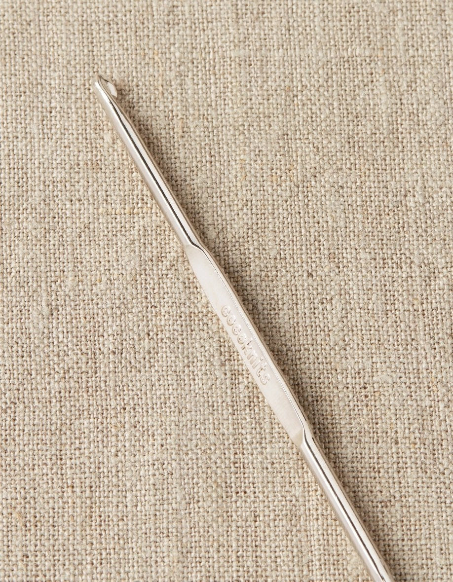 Steel repair hook on a beige fabric background