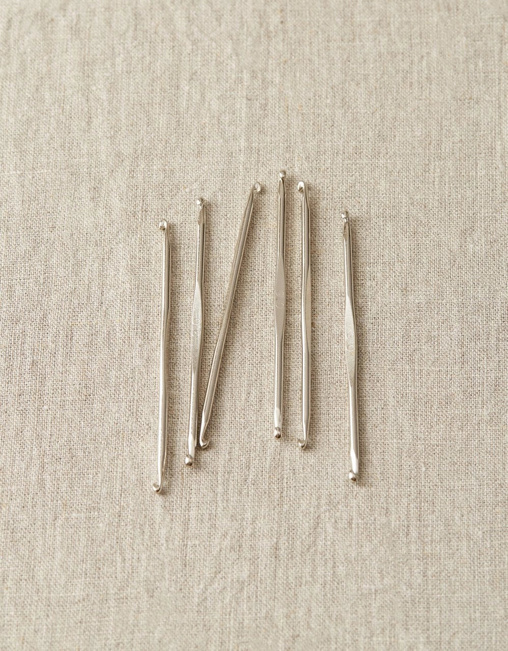 Set of nickel stitch fixers on a beige fabric background