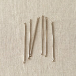 Set of nickel stitch fixers on a beige fabric background