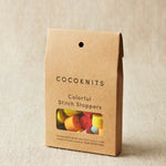 Cocoknits packaging with colorful stitch stoppers on a beige background