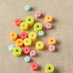 Rainbow colored stitch stoppers on a textured beige surface
