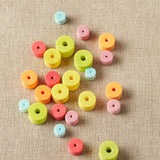 Rainbow colored stitch stoppers on a textured beige surface