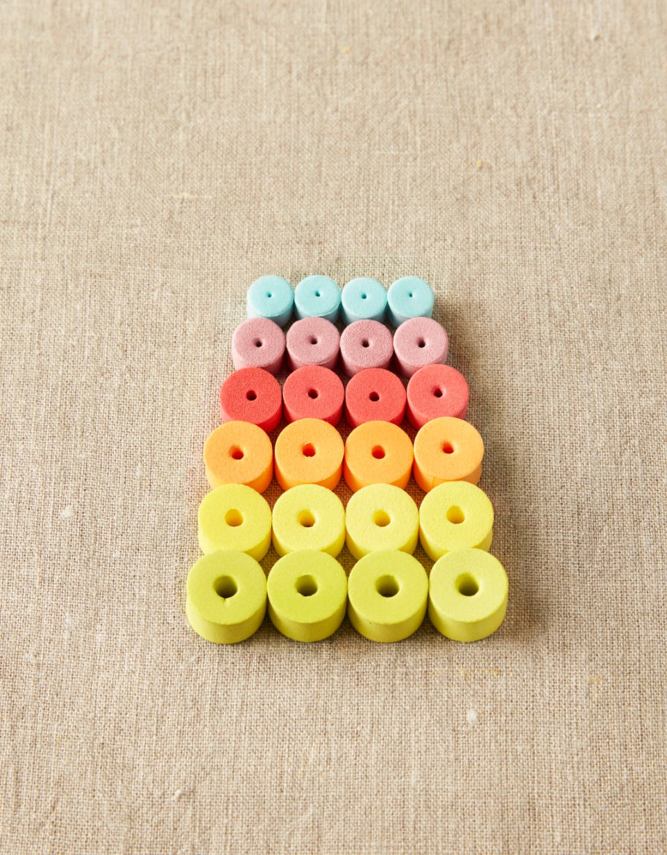 Colorful foam stitch stoppers arranged in a pattern on a beige fabric background
