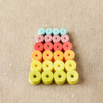 Colorful foam stitch stoppers arranged in a pattern on a beige fabric background