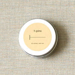 Tin container with 't-pins' label on a textured beige background