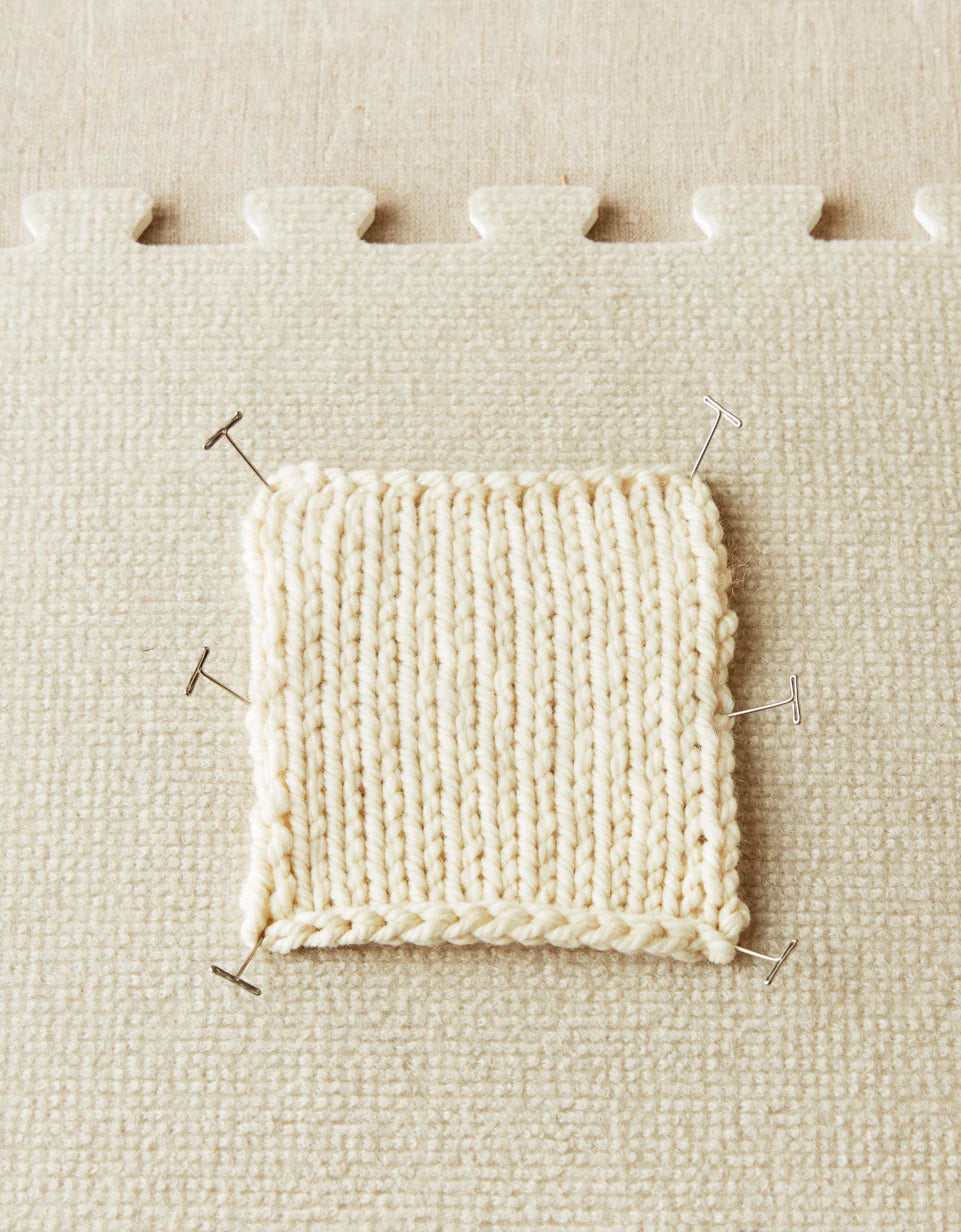 Knitted sample pinned to a fabric surface