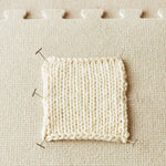 Knitted sample pinned to a fabric surface