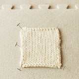 Knitted sample pinned to a fabric surface